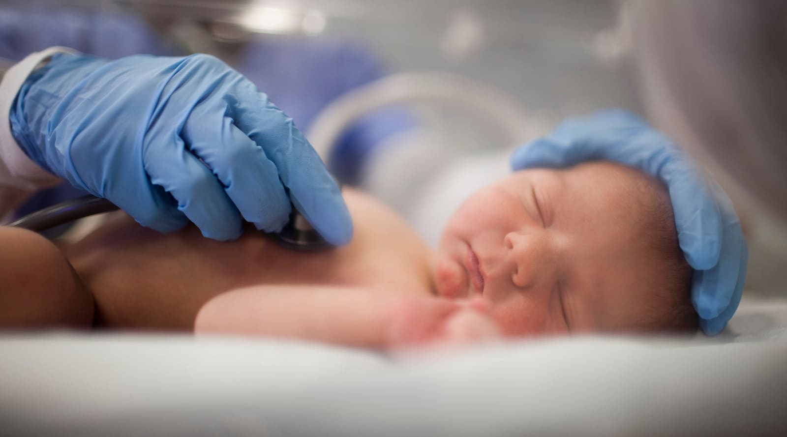 A doctor checking a premature baby’s heartbeat